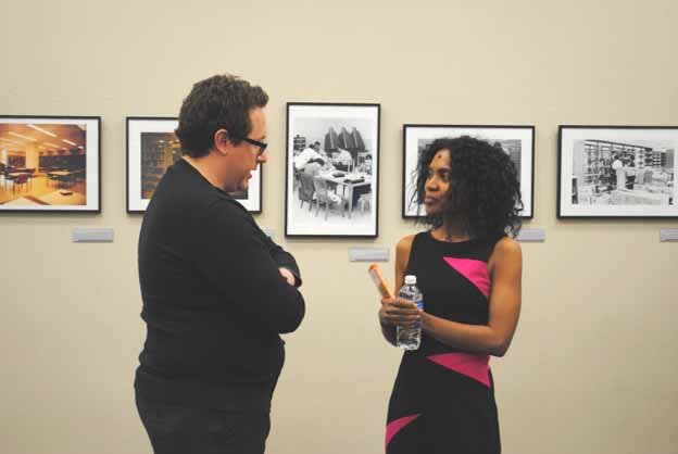Two people standing in front of a wall with pictures