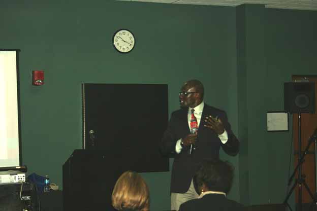 A person in a suit speaking to a group of people