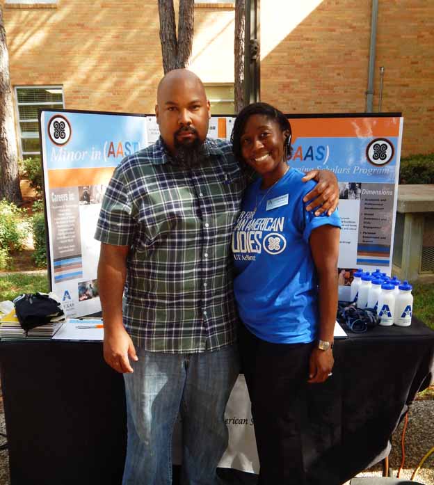 Two people standing next to a table posing for a photo