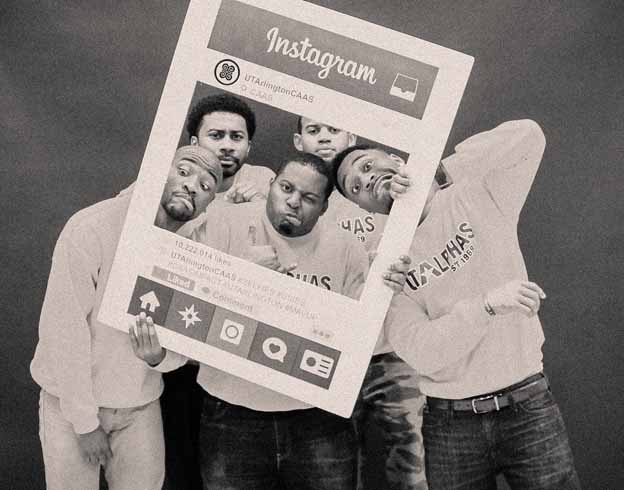 A group of men holding a instagram poster posing for a photo
