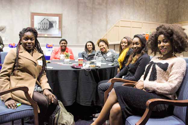 A group of women sitting around a round table posing for a photo