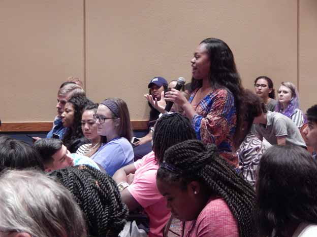 A person speaking into a microphone in front of a group of people